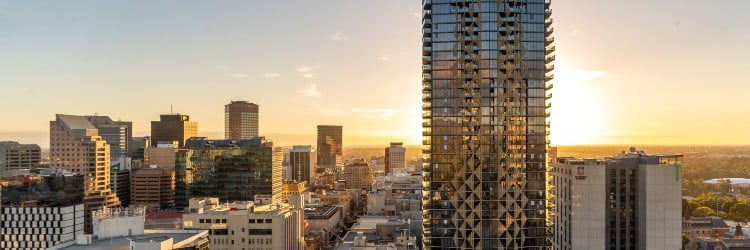Sunset view of a city skyline featuring modern skyscrapers and historic buildings, with vibrant colors illuminating the horizon.